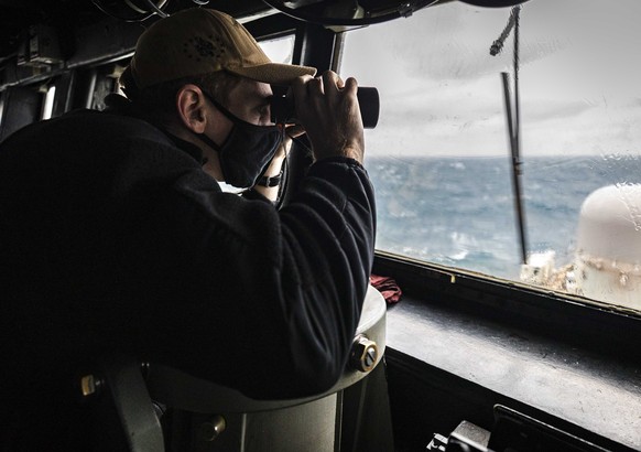 In this photo provided by U.S. Navy, Ensign Grayson Sigler, from Corpus Christi, TX., scans the horizon while standing watch in the pilot house as guided-missile destroyer USS John S. McCain conducts  ...