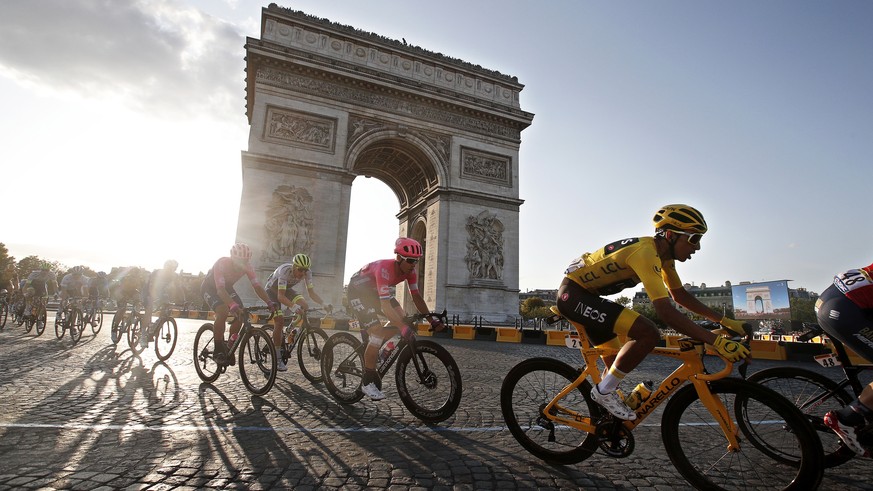 epaselect epa07746324 Colombia&#039;s Egan Bernal (R) of Team Ineos wears the overall leader&#039;s yellow jersey as he passes with the pack by the Arc de Triomphe during the 21st and final stage of t ...