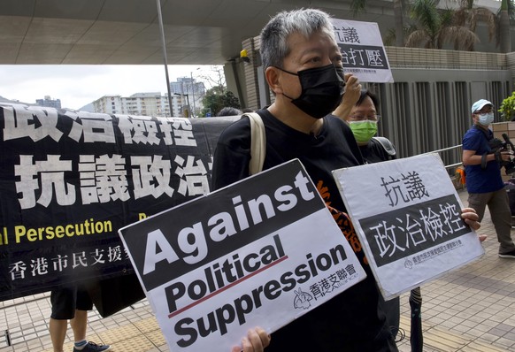 Pro-democracy activist Lee Cheuk-yan, center, holds placards as he arrives at a court in Hong Kong Thursday, April 1, 2021. Seven pro-democracy advocates, including media tycoon Jimmy Lai and veteran  ...