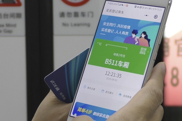 In this April 1, 2020, photo, a passenger holds up a green pass on their phone on a subway train in Wuhan in central China&#039;s Hubei province. Green is the &quot;health code&quot; that says a user  ...