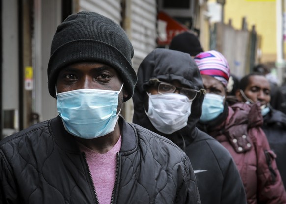 People wait for a distribution of masks and food from the Rev. Al Sharpton in the Harlem neighborhood of New York, after a new state mandate was issued requiring residents to wear face coverings in pu ...
