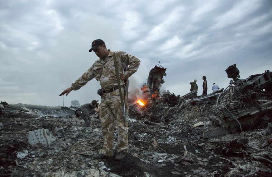FILE - In this July 17, 2014. file photo, people walk amongst the debris at the crash site of MH17 passenger plane near the village of Grabovo, Ukraine, that left 298 people killed. An international t ...