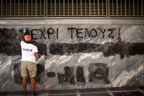 Ein Mann putzt in Athen ein Anti-Austeritäts-Tag weg. Die Entscheidung über die Zukunft Griechenlands liege jetzt bei der Regierung und den Gläubigern, schreibt der IWF im Bericht.