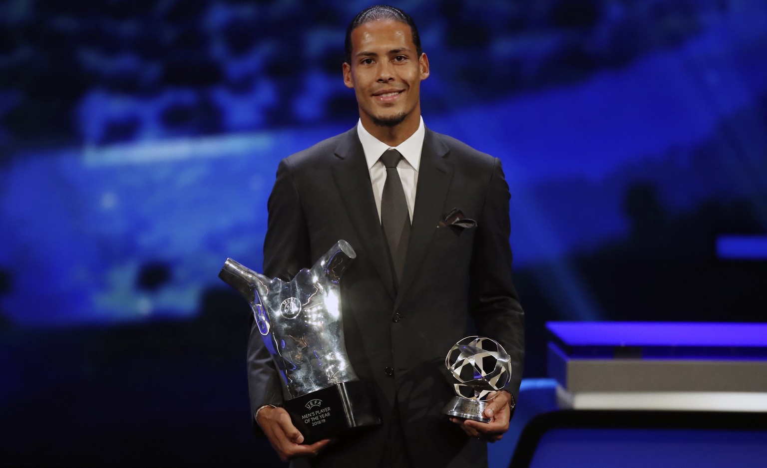 Dutch soccer player Virgil van Dijk of Liverpool holds the award of men&#039;s player of the year 2018/19 during the group stage draw at the Grimaldi Forum, in Monaco, Thursday, Aug. 29, 2019. (AP Pho ...