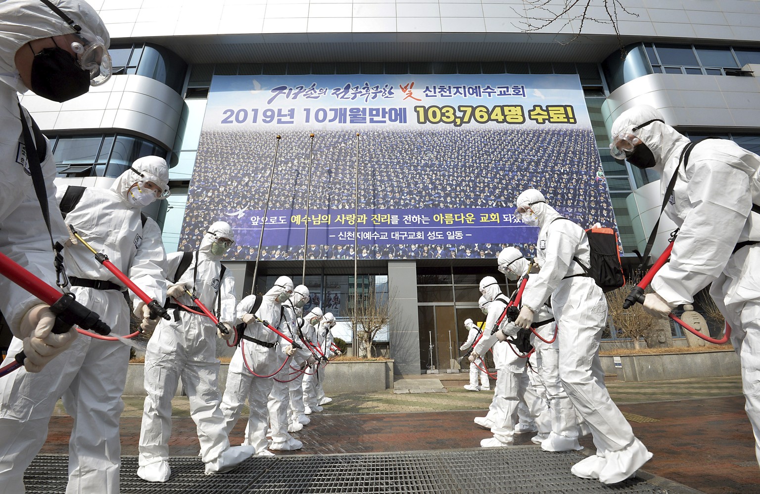 Army soldiers wearing protective suits spray disinfectant to prevent the spread of the coronavirus in front of a branch of the Shincheonji Church of Jesus in Daegu, South Korea, Sunday, March 1, 2020. ...