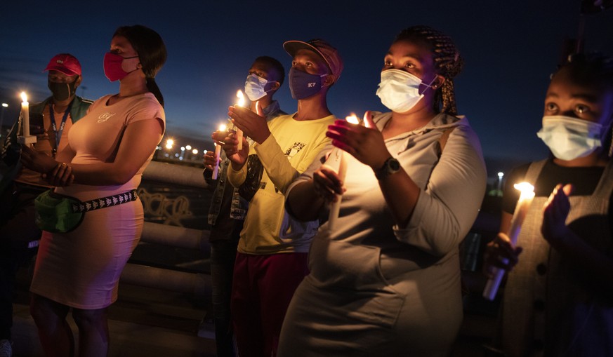 epa08913273 Members of the public stand with candles during a memorial for victims of the Covid-19 Coronavirus on New Year&#039;s eve who have died in the city during 2020, Johannesburg, South Africa, ...