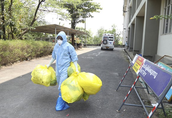 epa08189888 Indian medical staff wearing full protective suits hold medical waste as they exit from the coronavirus isolated ward of the Ernakulam Government Medical College in Kochi, Kerala, India, 0 ...