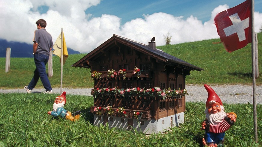 Ein Miniatur-Bauernhaus, Gartenzwerge und eine wehende Schweizerfahne stehen neben einem Wanderweg oberhalb von Schattdorf, Uri, aufgenommen im August 2001. (KEYSTONE/Sabina Bobst) === , === [Projekt  ...