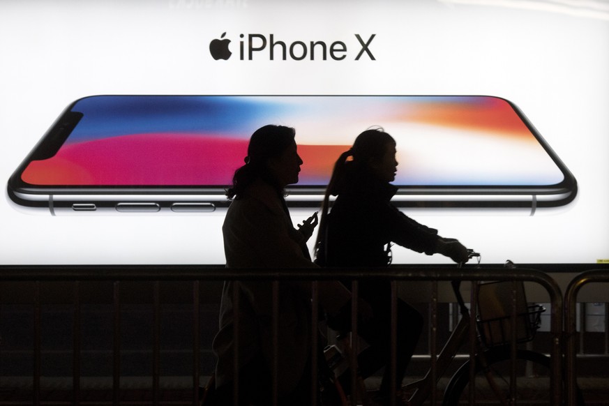 FILE - In this Monday, Nov. 6, 2017, file photo, residents pass by an advertisement for the iPhone X in Beijing, China. Apple shares have been falling in early 2018 on fears that the iPhone X has not  ...