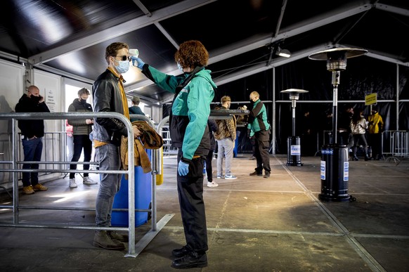 epa09085506 Visitors of a dance festival on the event site of Walibi Holland have their temperature measured on arrival prior to a trial event, in Biddinghuizen, the Netherlands, 20 March 2021.. The e ...