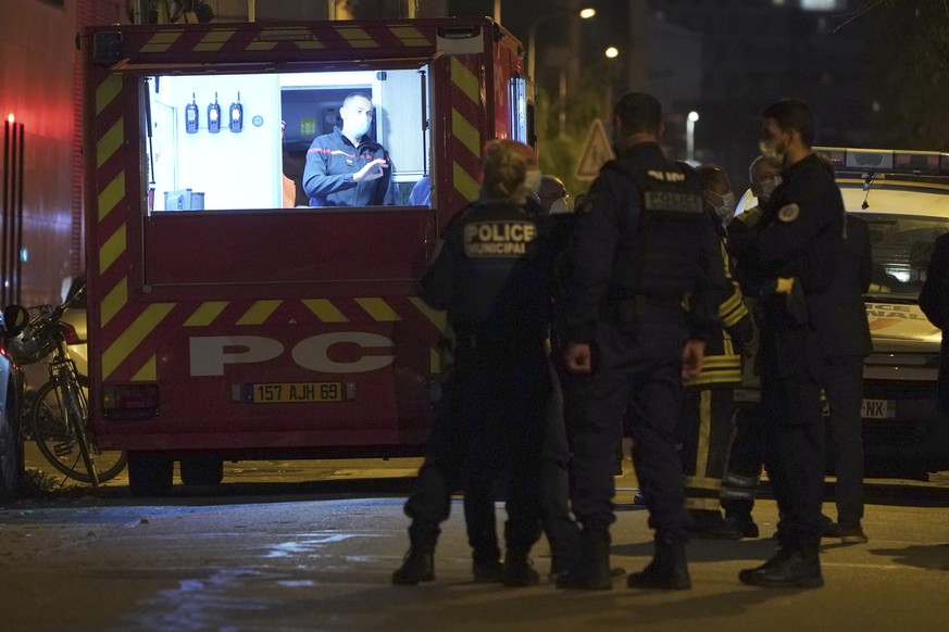 Police officers and rescue workers stand at the scene after a Greek Orthodox priest was shot Saturday Oct.31, 2020 while he was closing his church in the city of Lyon, central France. The priest, a Gr ...