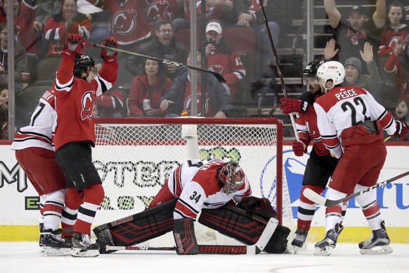 New Jersey Devils center Nico Hischier, second from left, of Switzerland, and left wing Marcus Johansson, back right, of Sweden, react after Johansson scored a goal on Carolina Hurricanes goaltender P ...