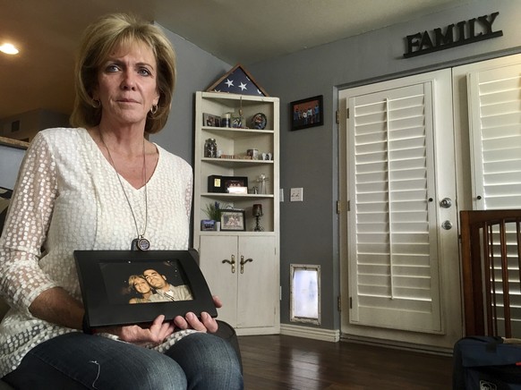 Mary Ann Mendoza poses for a photograph while holding a framed picture of herself and her son, Brandon Mendoza, on Thursday, March 2, 2017, at her home in Mesa, Ariz. Families who have lost loved ones ...