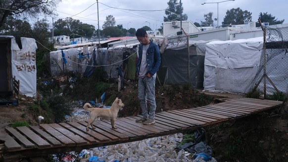A migrant walks over discarded garbage outside the perimeter of the overcrowded Moria refugee camp on the northeastern Aegean island of Lesbos, Greece, Wednesday, March 11, 2020. Camps on Lesbos and o ...