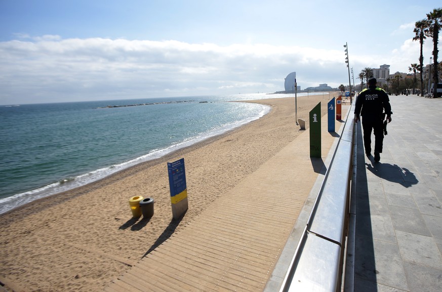 A police officer patrols preventing access to the beach in Barcelona, Spain, Sunday, March 15, 2020. Spain awoke to its first day of a nationwide quarantine on Sunday after the government declared a t ...
