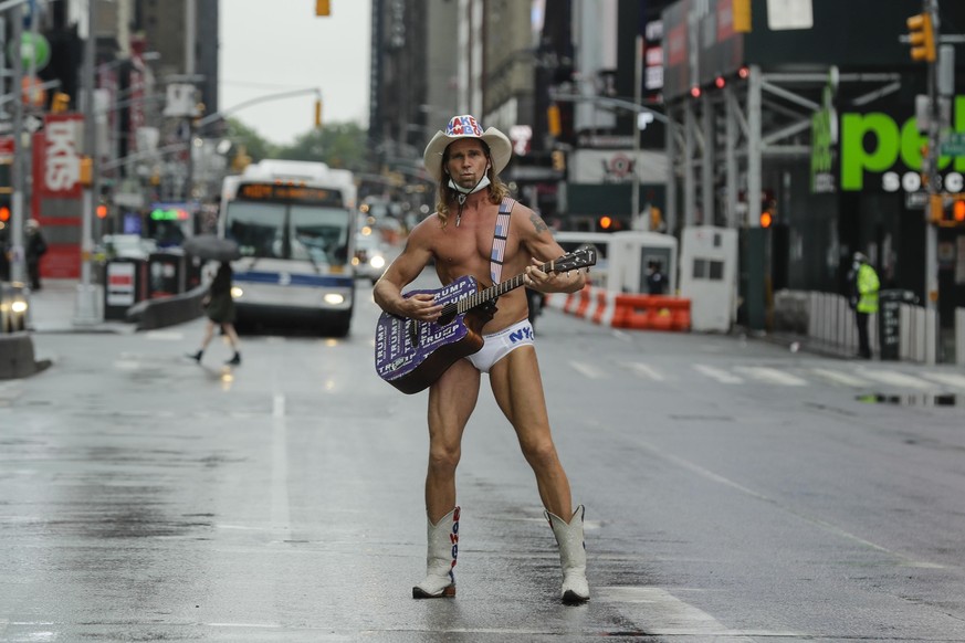 Robert Burck, who performs as the Naked Cowboy, poses for photographs in Times Square during the coronavirus pandemic , Saturday, May 23, 2020, in New York. (AP Photo/Frank Franklin II)