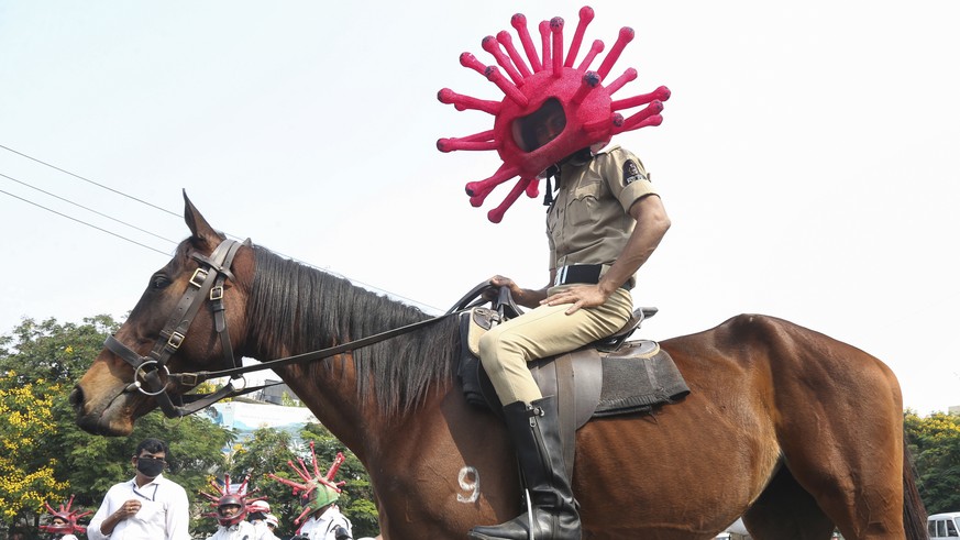 An Indian policeman wearing a virus themed helmet rides on a horse during an awareness rally aimed at preventing the spread of new coronavirus in Hyderabad, India, Thursday, April 2, 2020. The new cor ...