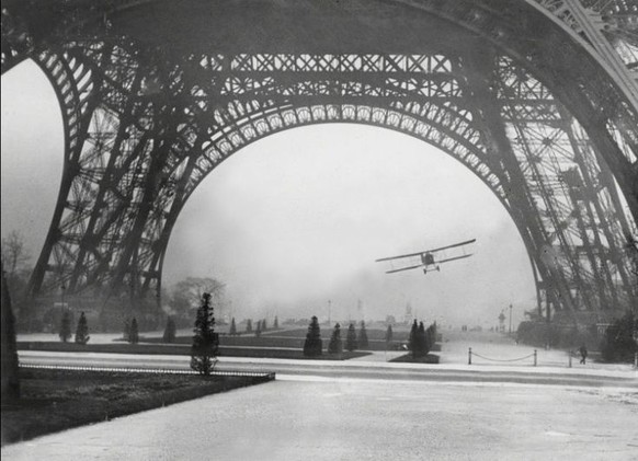 Leon Collet durchfliegt die Bögen des Eiffelturms, 1926. Der Pilot kam beim Manöver ums Leben, weil seine Maschine mit einem Antennenkabel kollidierte und abstürzte.