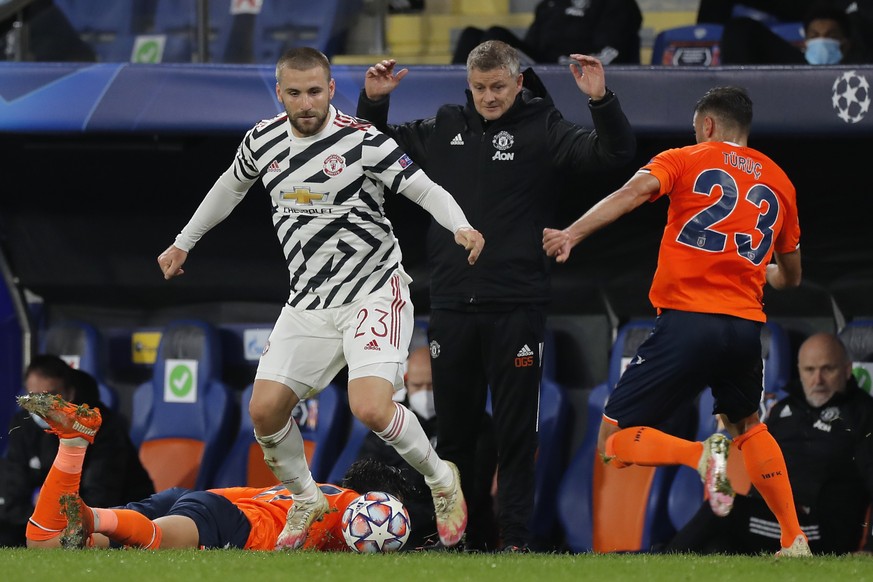 Manchester United&#039;s manager Ole Gunnar Solskjaer, background, gestures as Manchester United&#039;s Luke Shaw, left, fights for the ball with Basaksehir&#039;s Aziz Behich during the Champions Lea ...