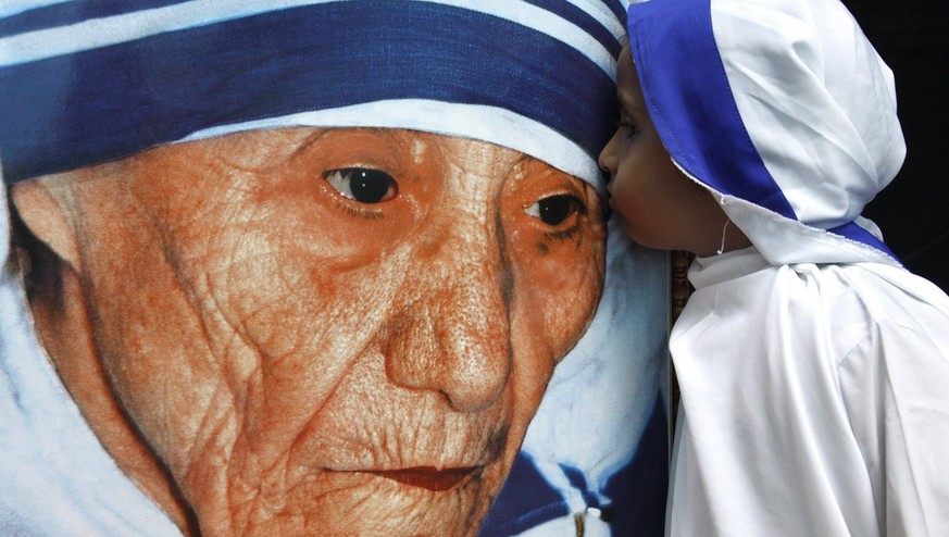 Eine Kindernonne küsst das Bild von Mutter Teresa.