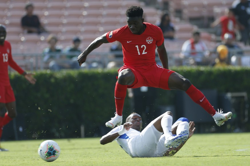 Canada midfielder Alphonso Davies (12) leaps over Martinique midfielder Daniel Herelle during the first half of a CONCACAF Gold Cup soccer match in Pasadena, Calif., Saturday, June 15, 2019. (AP Photo ...
