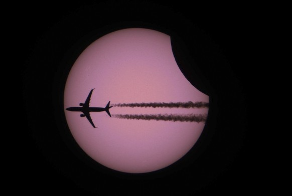 HANDOUT - An airplane is silhouetted against a partial solar eclipse, in Geneva, Switzerland, on Thursday, June 10, 2021. (The Astronomical Society of Geneva/Eric Achkar) *** NO SALES, DARF NUR MIT VO ...