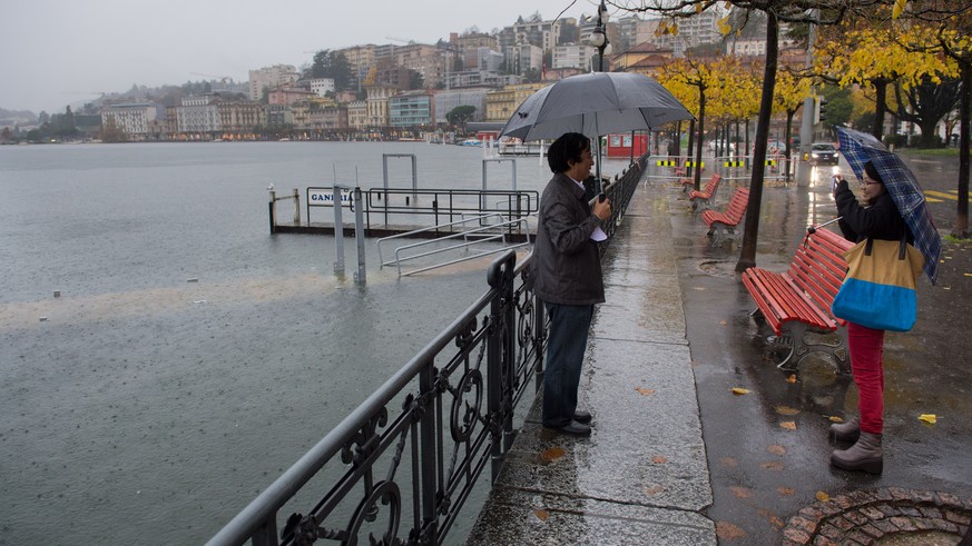 Touristen mit Regenschirmen stehen im Regen am Ufer des Lungolago von Lugano und machen Fotos, am Samstag, 15. November 2014. Das Tessin kommt nicht zur Ruhe. Nach einer kurzen Verschnaufpause hat in  ...