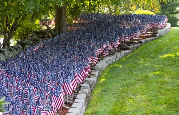 epa08698023 Over 8000 flags, representing the number of Covid-19 deaths in Massachusetts, are seen placed in the yard of Mike Labbe in Grafton, Massachusetts, USA 25 September 2020. Labbe started plan ...