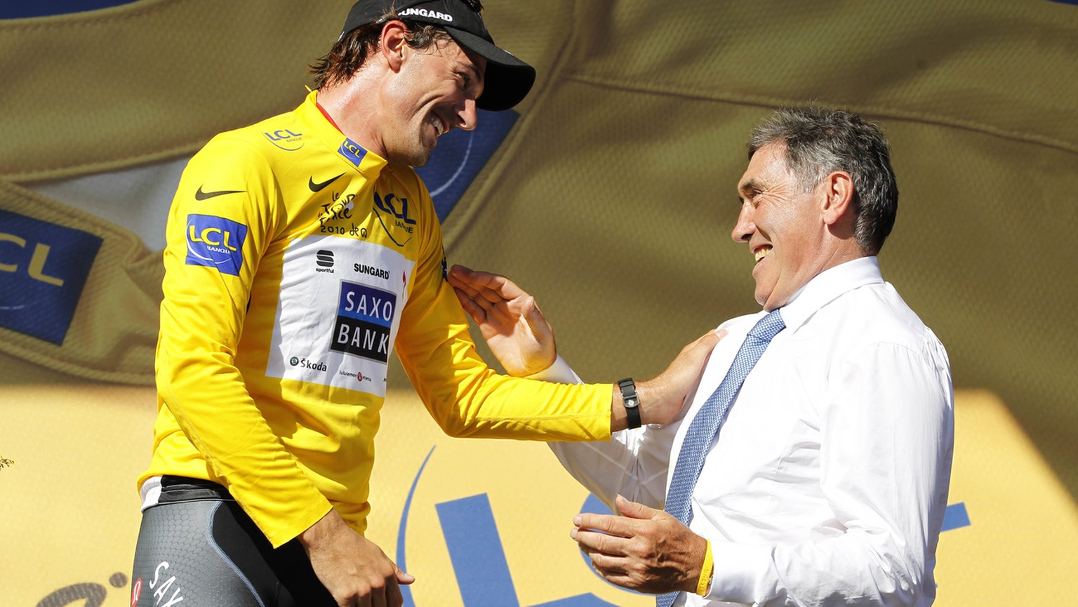 Fabian Cancellara of Switzerland, wearing the overall leader&#039;s yellow jersey, left, and Belgium cyclist and Tour de France winner Eddy Merckx, right, react on the podium after the first stage of  ...