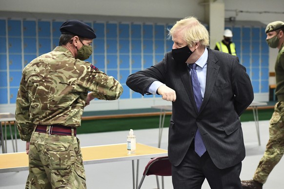 Britain&#039;s Prime Minister Boris Johnson elbow bumps a member of the military as he meets troops setting up a vaccination centre in the Castlemilk district of Glasgow, on his one day visit to Scotl ...