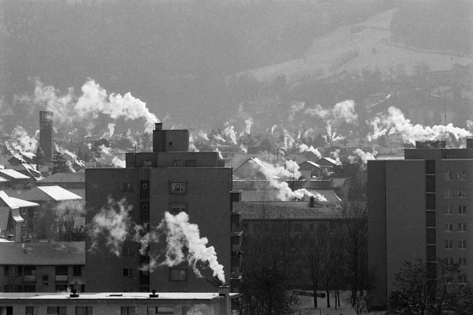Rauchende Kamine von Privathaeusern bei winterlichen Temperaturen in der Stadt Chur, aufgenommen am 12. Januar 1987. (KEYSTONE/Arno Balzarini)