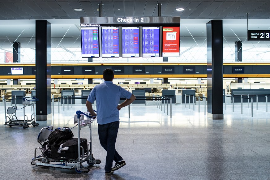 A passenger is looking at the departures board at the Zurich Airport in Zuerich, Switzerland, Tuesday, March 10, 2020. The spreading of the Coronavirus has effects on the passenger volume at Switzerla ...