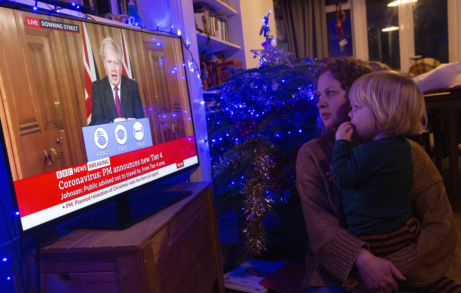 epa08894231 Leanne Hall and her son Alex watch as Britain&#039;s Prime Minister Boris Johnson delivers a televised statement in London, Britain, 19 December 2020. Britain&#039;s Prime Minister Boris J ...