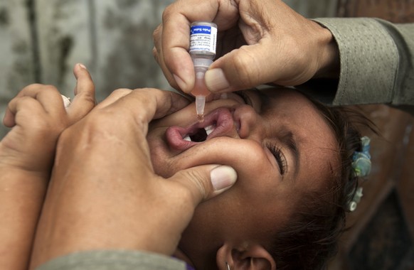 A Pakistani health worker gives a polio vaccine to children under tight security, in Peshawar, Pakistan, Monday, Oct. 24, 2016. Polio remains endemic in Pakistan after the Taliban banned vaccinations, ...
