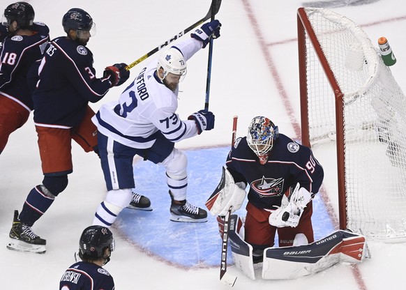 Columbus Blue Jackets goaltender Elvis Merzlikins (90) makes a save as Toronto Maple Leafs left wing Kyle Clifford (73) battles with Blue Jackets defenseman Seth Jones (3) during the third period of a ...
