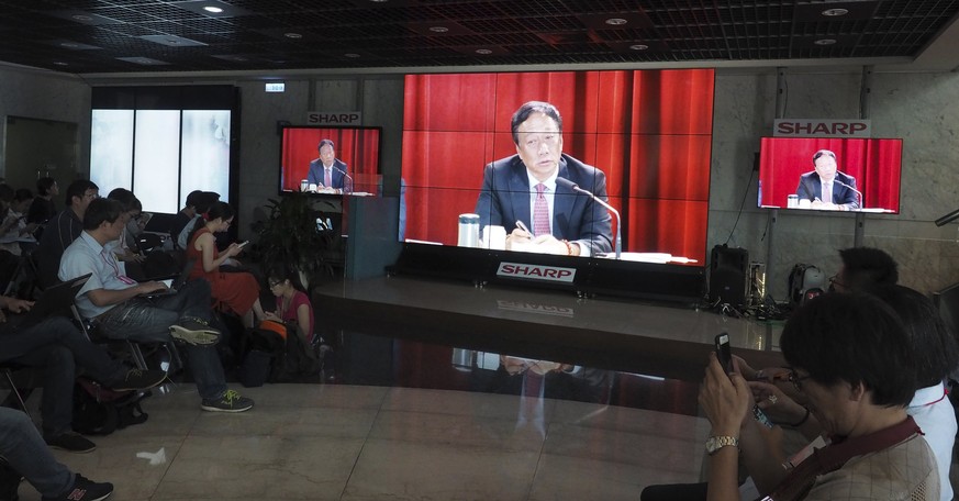 epa06042321 People look on as screens display Hon Hai Group Chairman Terry Gou attending a Hon Hai shareholders meeting, in New Taipe City, Taiwan, 22 June 2017. Gou said that Toshiba&#039;s sale of i ...