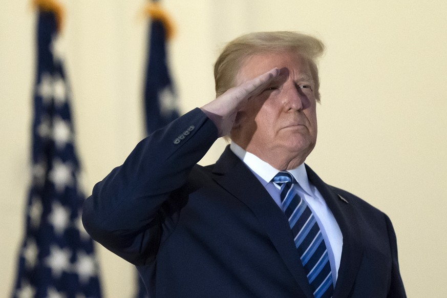 President Donald Trump salutes as he stands on the Blue Room Balcony upon returning to the White House Monday, Oct. 5, 2020, in Washington, after leaving Walter Reed National Military Medical Center,  ...