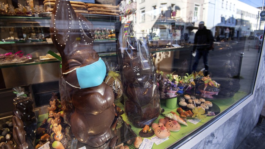 A chocolate Easter bunny with a face mask stands in a shop window of a confectioner&#039;s shop as a reaction of the novel coronavirus outbreak in Stuttgart, Germany, Friday, March 27, 2020. The new c ...
