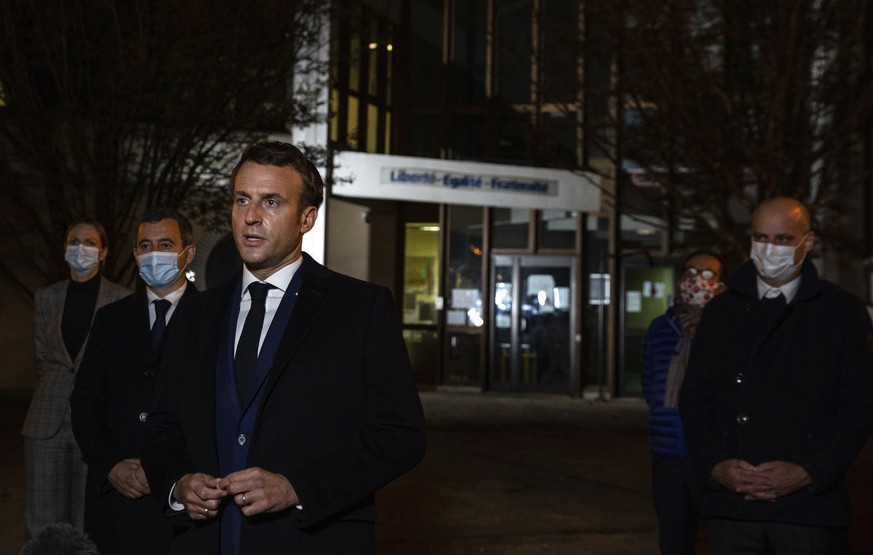 French President Emmanuel Macron, flanked by French Interior Minister Gerald Darmanin, second left, and French Education Minister Jean-Michel Blanquer, right, speaks in front of a high school Friday O ...