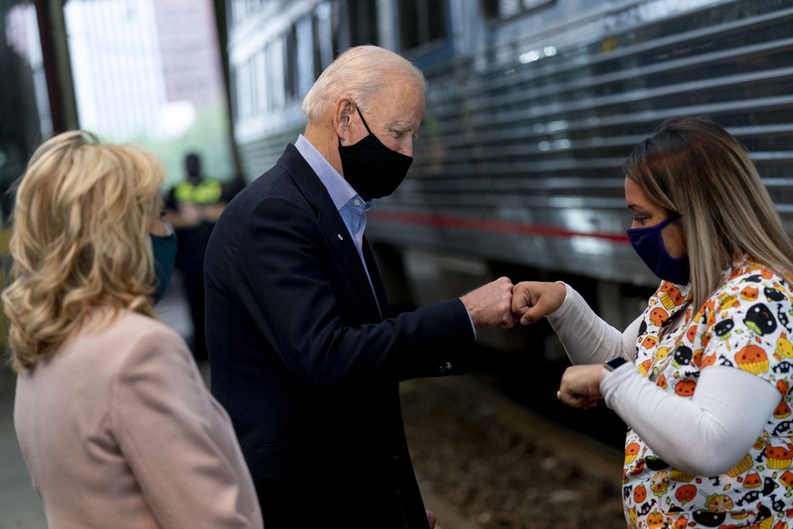 Democratic presidential candidate former Vice President Joe Biden, accompanied by his wife Jill Biden, left, fist bumps a supporter before boarding his train at Amtrak&#039;s Pittsburgh Train Station, ...