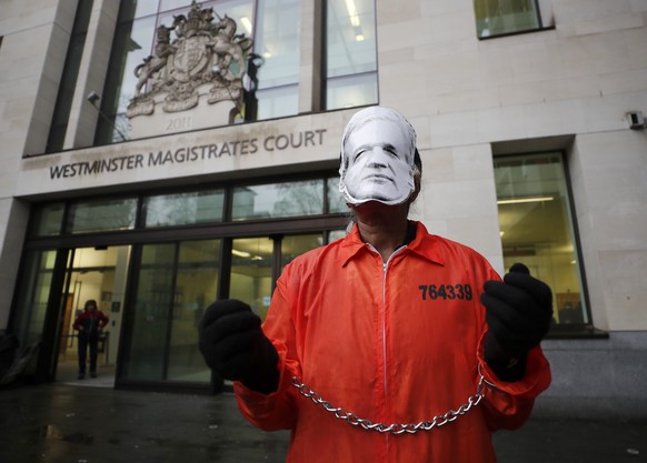 A supporter of WikiLeaks founder Julian Assange protests in front of a prison van entering Westminster Magistrates Court in London, Friday, Dec. 20, 2019. Assange is expected to appear in person befor ...