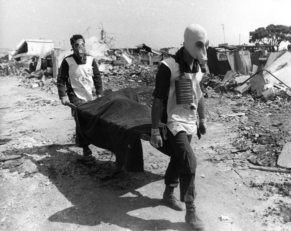 Fast alle Opfer waren Zivilisten: Helfer mit Gasmasken tragen eine Leiche weg.