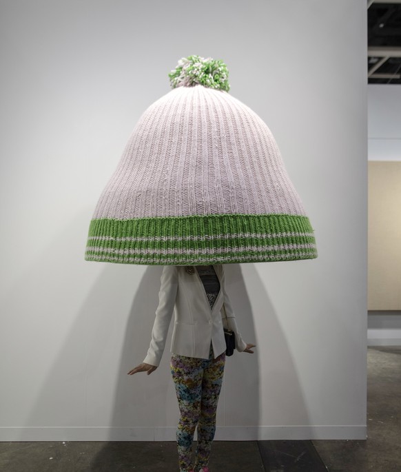 epa07466688 A visitor stands under an art piece by Erwin Wurm entitled &#039;Title to be determined (Austrian mountain cap)&#039; displayed at the Art Basel in Hong Kong, China, 27 March 2019. Art Bas ...