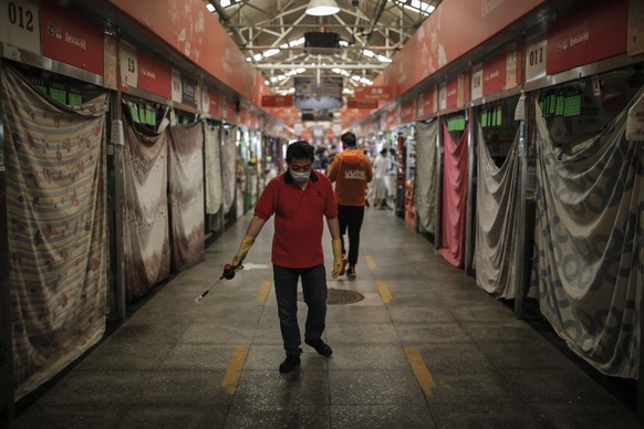 epa08495426 A worker wearing protective face mask sprays disinfectant besides many closed fruit stalls in a market in Beijing, China, 19 June 2020. Chinese authorities are trying to find the source of ...
