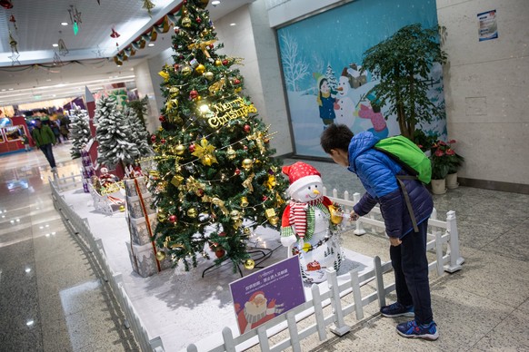 epa06404010 A Chinese young boy looks at a Christmas tree at a shopping mall in Beijing, China, 23 December 2017. While Christmas is not celebrated by most Chinese in the secular China, Christmas ligh ...