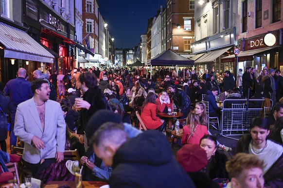 People sit at setup tables outside pubs in Soho, in London, on the day some of England&#039;s third coronavirus lockdown restrictions were eased by the British government, Monday, April 12, 2021. Pubs ...
