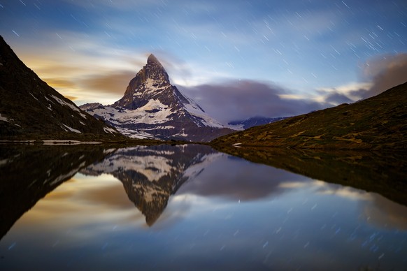 epa06830575 The the iconic Matterhorn mountain, peaking at 4478m, is pictured with a long exposure after the moonset from the Riffelsee Lake in the Riffelberg area above the alpine village of Zermatt, ...