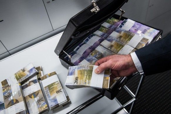 Ein Mann fuellt einen Aktenkoffer mit Tausendernoten und Zweihundert-Franken-Noten neben Schliessfaechern fotografiert in einem Safe einer Bank in Lugano am Mittwoch, 30 November 2016. (KEYSTONE/TI-PR ...
