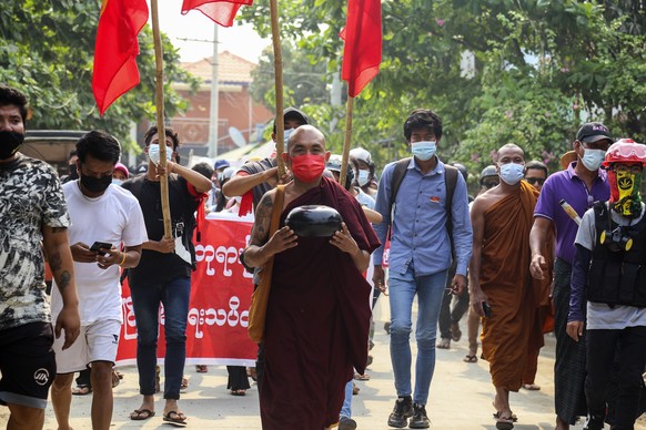 epa09107953 A monk (C) holds an alm bowl while marching together with demonstrators during a protest against the military coup in Mandalay, Myanmar, 31 March 2021. Anti-coup protests continued in Myan ...