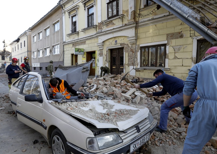 epaselect epa08909605 People and soldiers clean the rubble next to car and buildings damaged in an earthquake in Petrinja, Croatia, 29 December 2020. A 6.4 magnitude earthquake struck around 3km west  ...